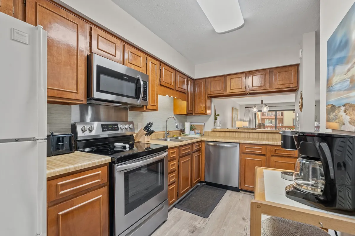 A spacious, modern kitchen with stainless steel appliances, wooden cabinetry, generous countertops, and a kitchen island. The kitchen is bright and organized, ideal for preparing meals or gathering with loved ones.