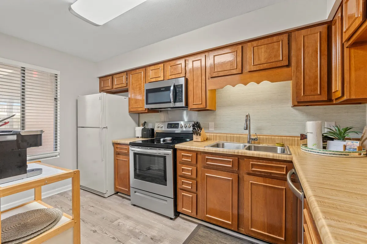 A bright, fully equipped kitchen featuring clean kitchen cabinets, sleek stainless steel appliances, ample countertop space, and a welcoming layout. The space is styled for both function and warmth, inviting guests to cook, bake, and gather.