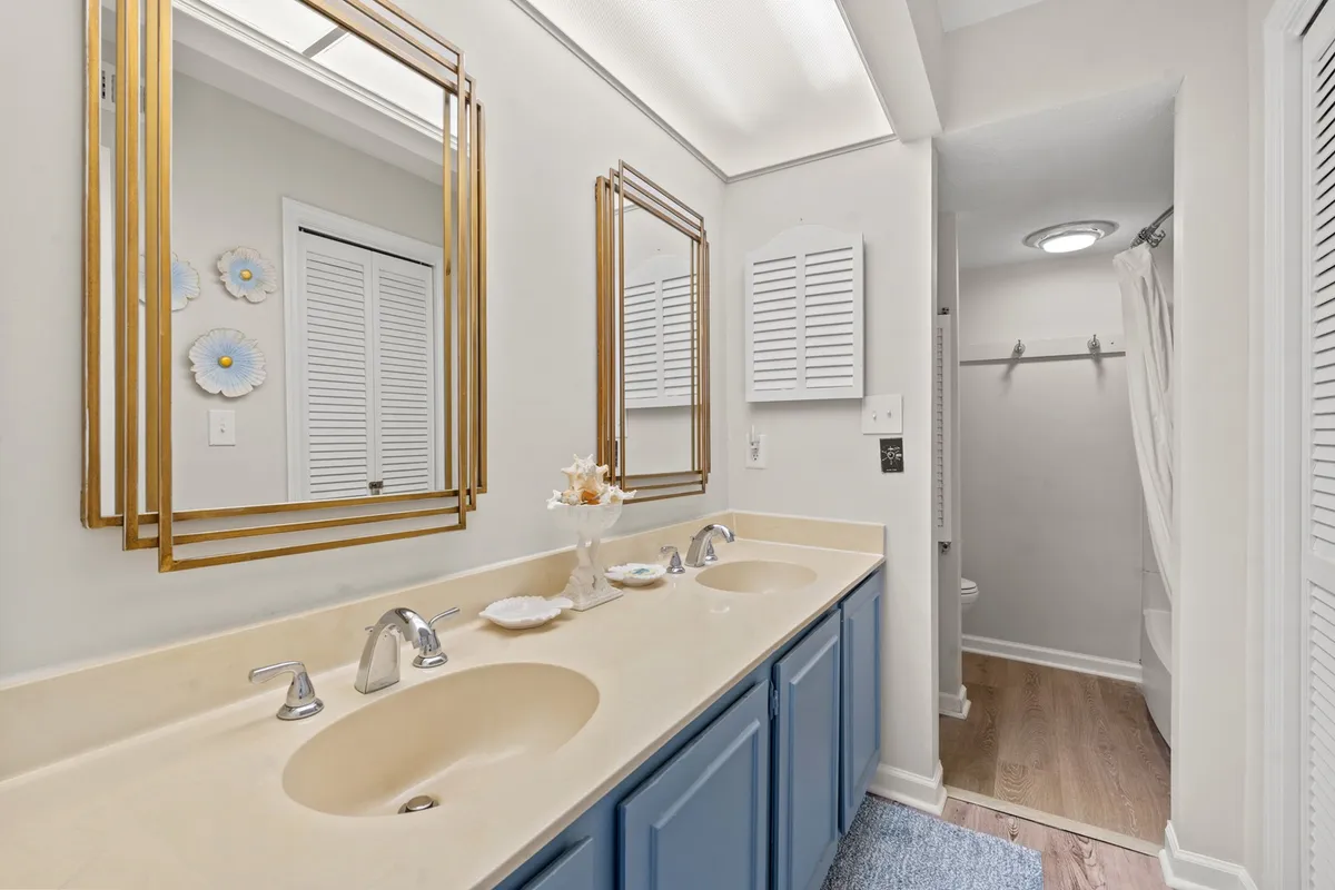 A bright, well-appointed bathroom featuring dual sinks, large framed mirrors, and tasteful decorative wall accents. The space feels both functional and inviting, with ample room for morning and evening routines.